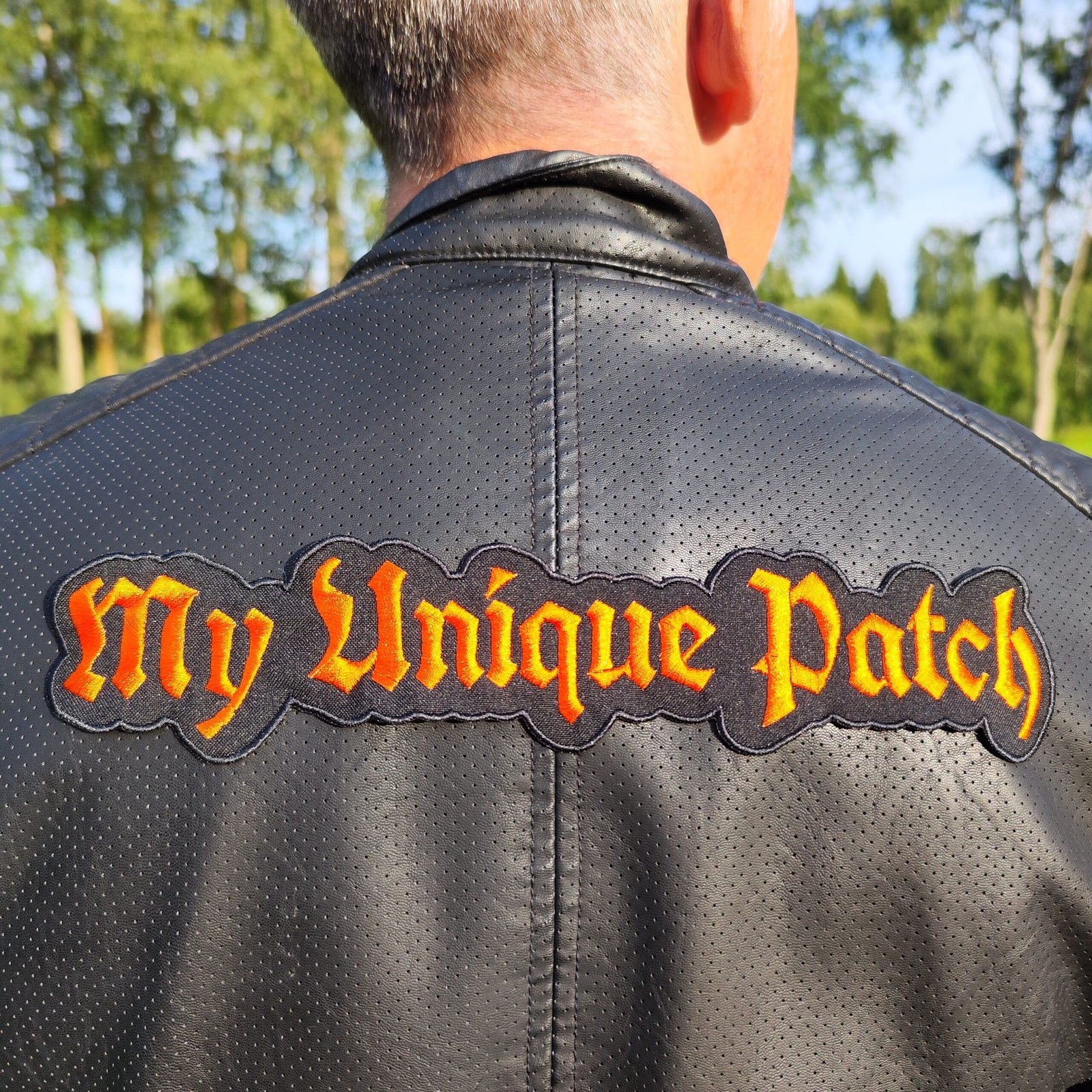 large patch with custom gothic font text for back of a jacket, a men in a black jacket with a patch by Mottopatch